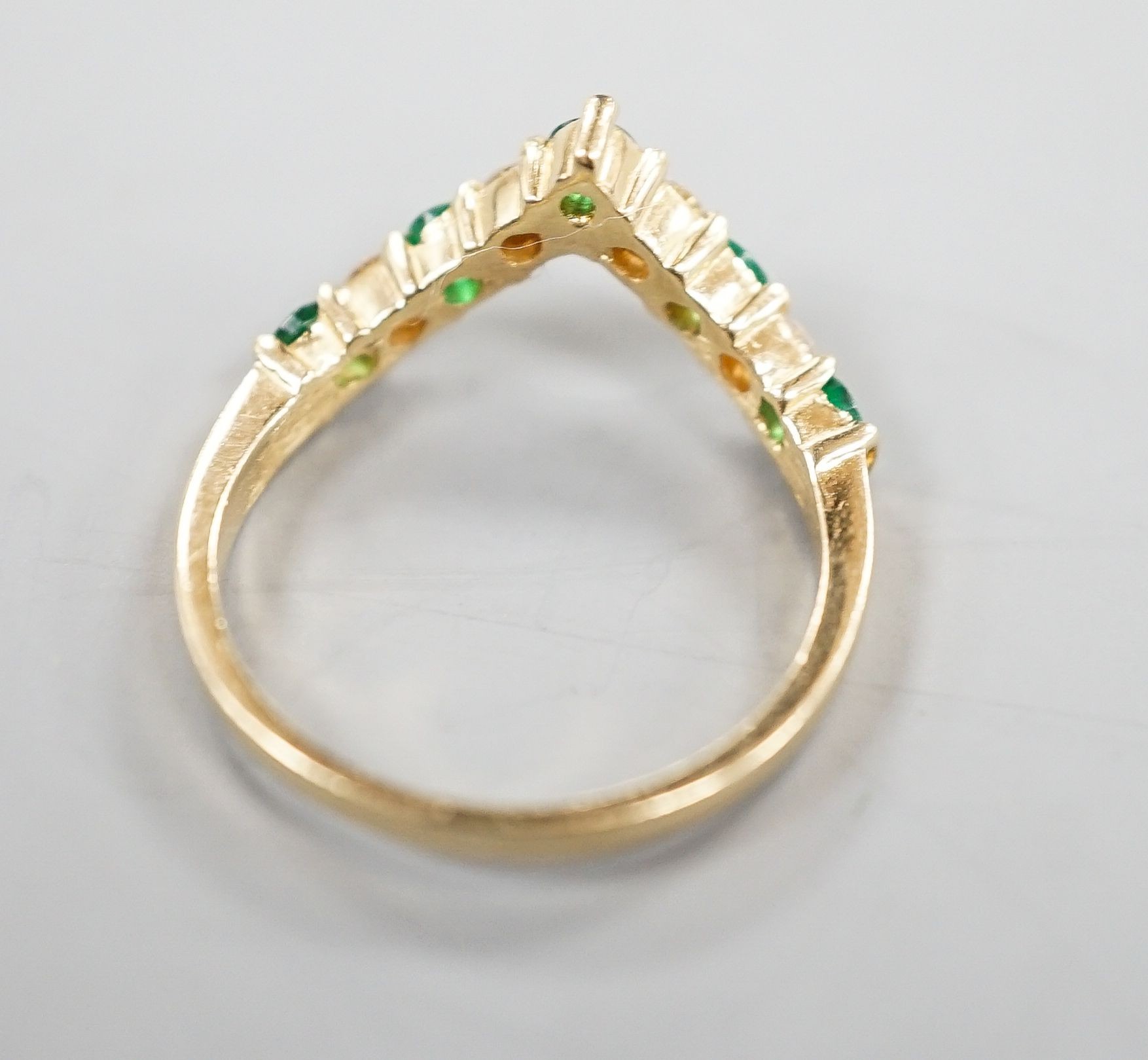 A modern 14k yellow metal, five stone emerald and four stone diamond set wishbone ring, size M, gross 2.3 grams.